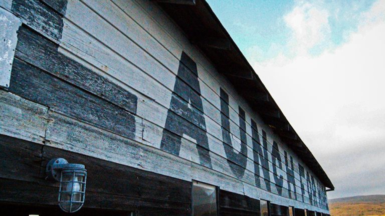 image of a boat house on Tomales Bay, CA, with the words "LAUNCH FOR HIRE" in large, fading letters painted on its side